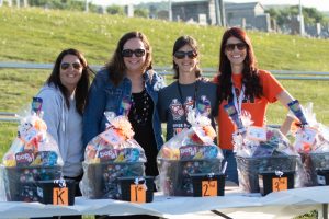 elementary teachers and staff standing outside behind raffle baskets
