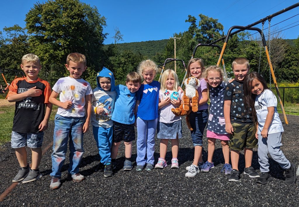 kindergarten students on play ground smiling and hugging each other