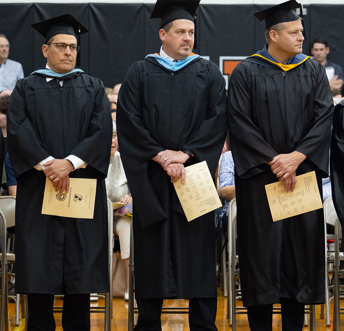 three teachers in graduation gowns and caps at graduation