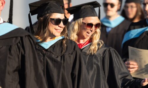 teachers in graduation gowns waving
